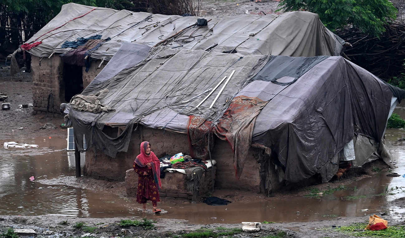 A girl walks through a pool of water near makeshift shelters after heavy rainfall in Peshawar, Pakistan, on April 3, 2026. (AFP/File)