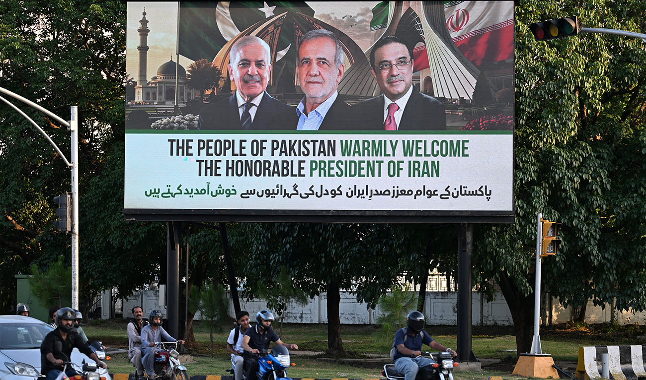 Commuters ride past an electronic board featuring Iran's President Masoud Pezeshkian (C), Pakistan's Prime Minister Shehbaz Sharif (L) and President Asif Ali Zardari, displayed along a street in Islamabad on June 22, 2026 on the eve of Pezeshkian's visit to Pakistan amid the US-Iran peace talks. (AFP)
