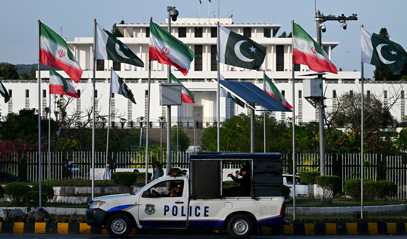 Police personnel ride past the national flags of Pakistan and Iran fluttering outside the President House in Islamabad, Pakistan, on June 22, 2026. (AFP)