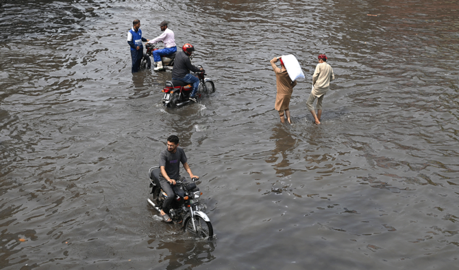 Commuters wade through a flooded street after heavy monsoon rains in Lahore on August 3, 2025. (AFP/File)