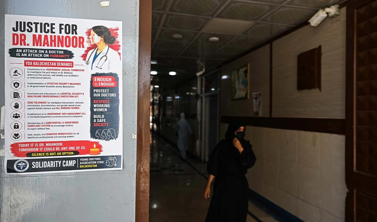 A woman walks past a poster displayed by medical practitioners to express solidarity with acid attack victim doctor Mahnoor Nasir, at a hospital in Quetta on June 9, 2026. (AFP)