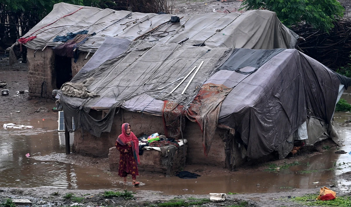 A girl walks through a pool of water near makeshift shelters after heavy rainfall in Peshawar, Pakistan, on April 3, 2026. (AFP/File)