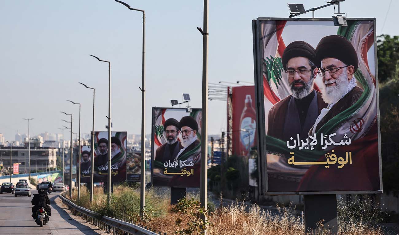 Cars and motorbikes drive past billboards showing Iran’s new Supreme Leader Ayatollah Mojtaba Khamenei (L) and his late father Ali Khamenei (R), with the slogan “Thank you, loyal Iran,” erected along the highway leading to Rafic Hariri International Airport in Beirut on June 22, 2026. (AFP/ file)