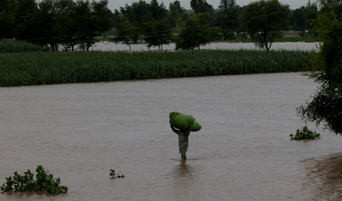 A man carries a sack of fodder on his head as he walks along a flooded road, following monsoon rains and rising water levels of the Chenab River, in Patraki village, Chiniot district, Punjab province, Pakistan, August 30, 2025. (Reuters/File)