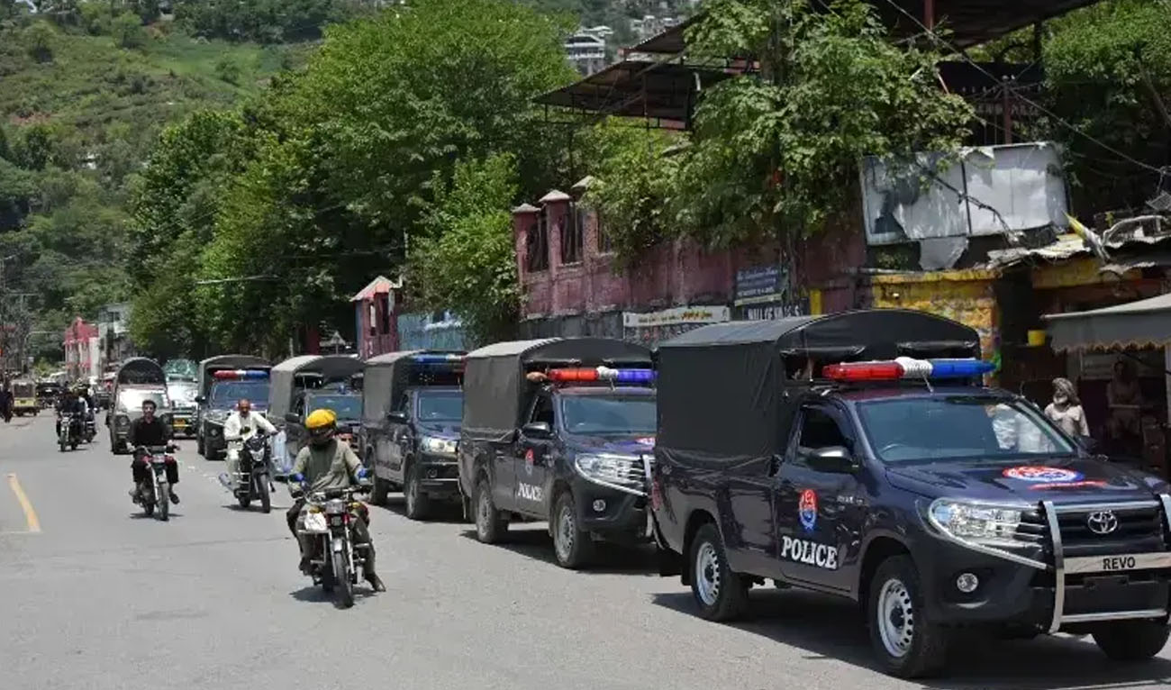 Commuters ride past security personnel as they patrol a street ahead of a protest by the Joint Awami Action Committee (JAAC) in Muzaffarabad, on June 7, 2026. (AFP/File)