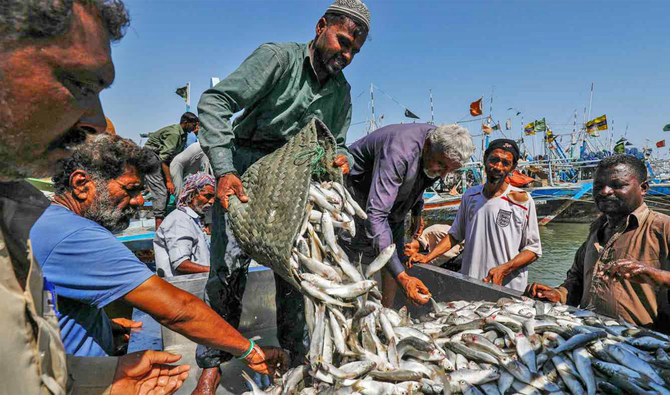 Fishermen unload baskets of fish from a boat after they returned with the day's catch at a harbor in Ibrahim Hyderi fishing village on the outskirts of Karachi, Pakistan, on April 29, 2020. (REUTERS/File)