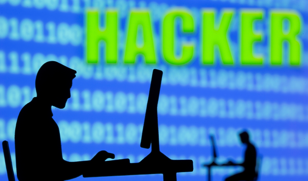 The 3D printed models of men working on computers are seen in front of displayed binary code and the words “Hacker” in this illustration taken on July 5, 2021. (REUTERS/File)