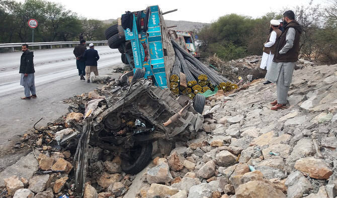 Bystanders stand next to the wreckage of a passenger van and a truck after an accident in Kohat district of northern Khyber Pakhtunkhwa province on February 3, 2023. (AFP/File)
