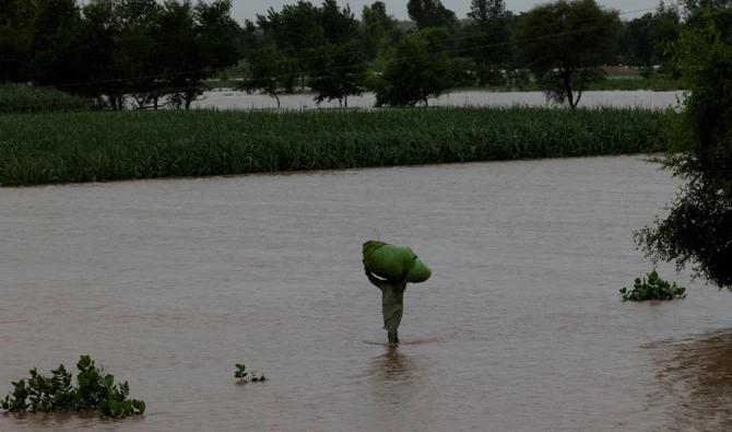 A man carries a sack of fodder on his head as he walks along a flooded road, following monsoon rains and rising water levels of the Chenab River, in Patraki village, Chiniot district, Punjab province, Pakistan, August 30, 2025. (Reuters/File)