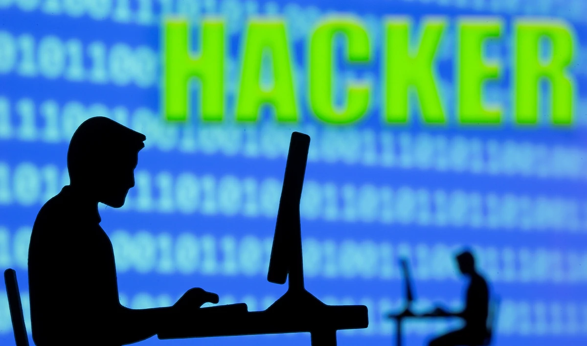 The 3D printed models of men working on computers are seen in front of displayed binary code and the words “Hacker” in this illustration taken on July 5, 2021. (REUTERS/File)