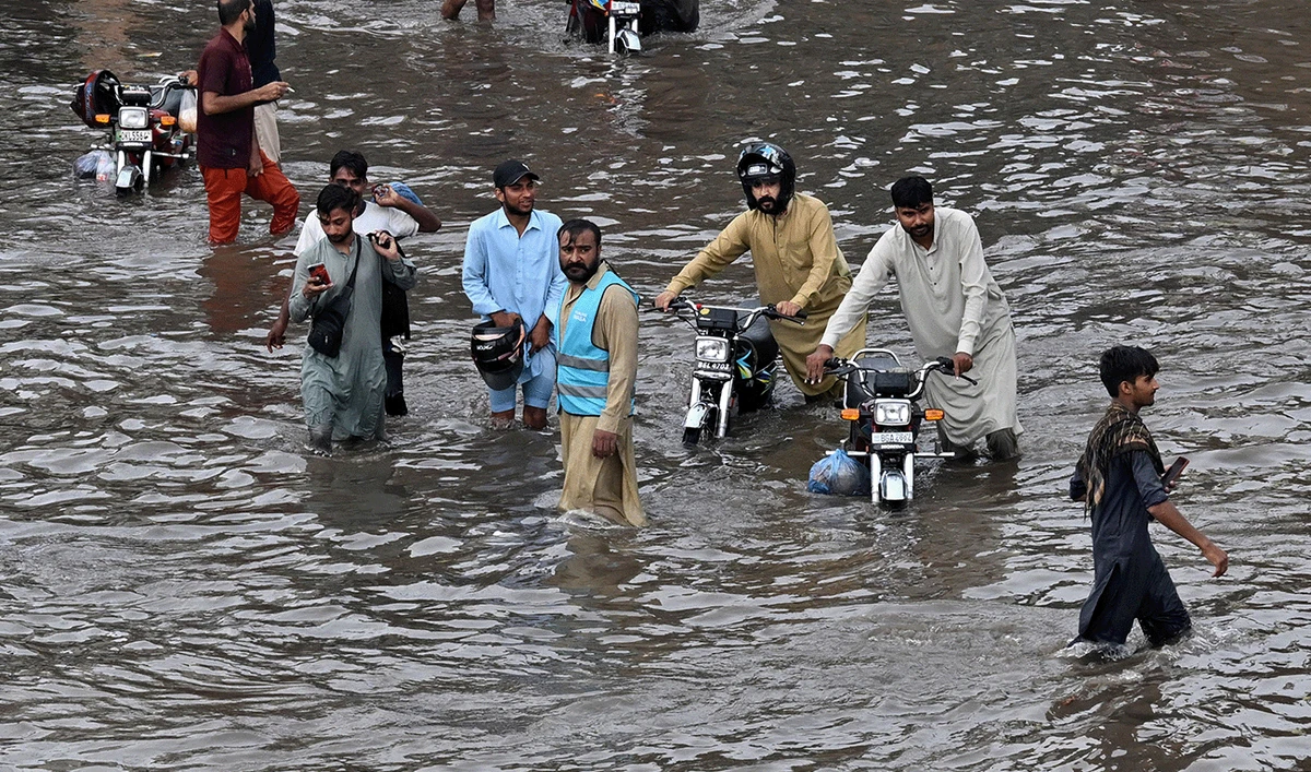 People wade through a flooded street after heavy rainfall in Lahore on July 22, 2026. (AFP)