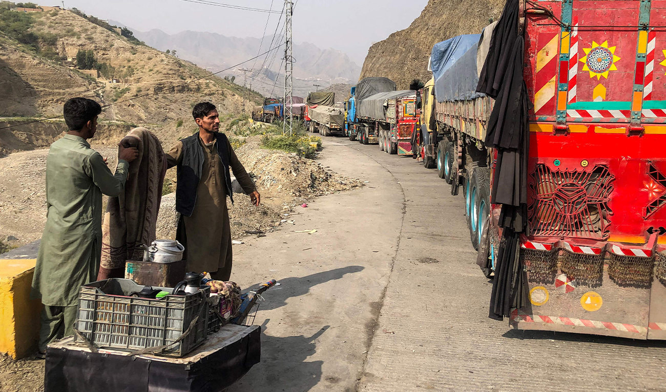 A tea vendor stands near the stalled vehicles near the closed Pakistan-Afghanistan border town of Torkham on October 19, 2025. (AFP/File)