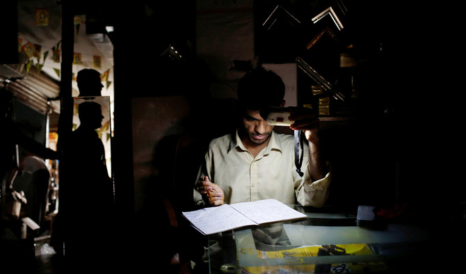 A man uses battery powered light while working at a shop during a power breakdown in Karachi, Pakistan on May 16, 2018. (Reuters/File)
