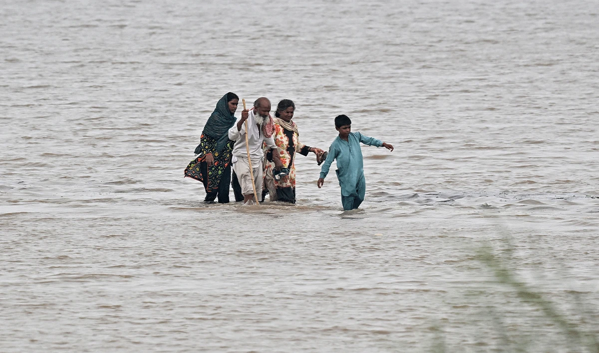 People wade through a flooded area after heavy monsoon rains induced a rise in the water level of the Ravi river in Pakistan's Muridke on July 28, 2026. (AFP/File)