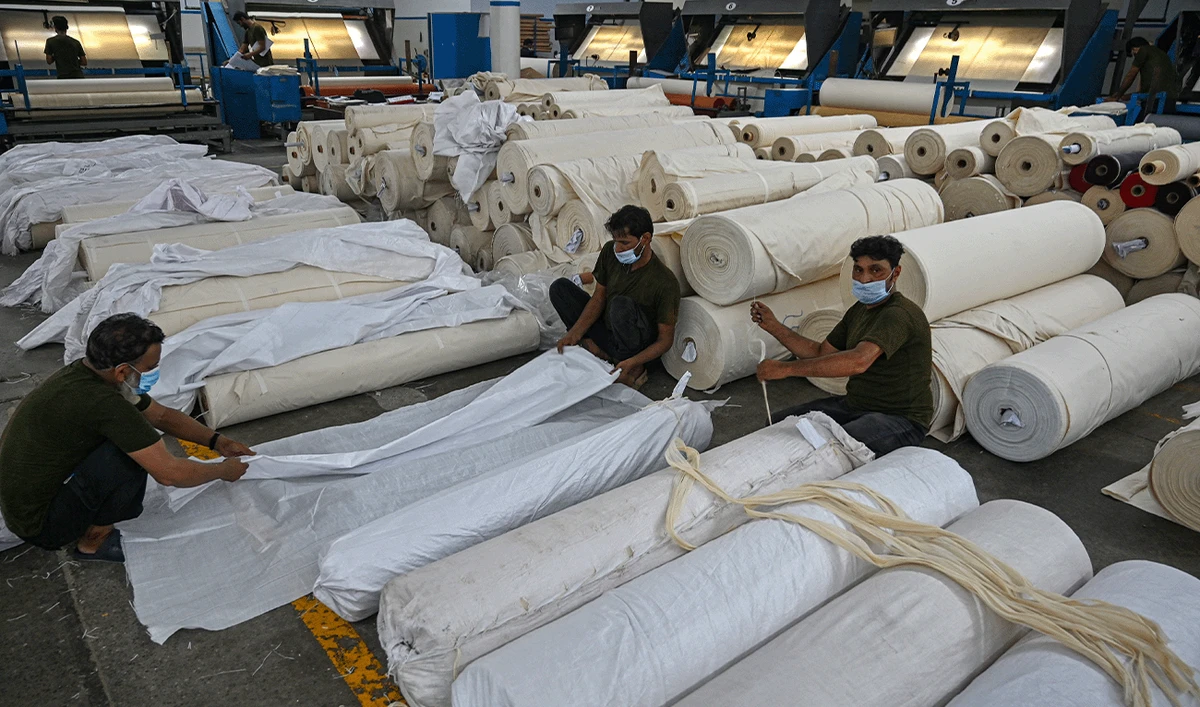 In this picture taken on July 20, 2023, workers pack fabric rolls at the Kohinoor Textile Mills in Lahore, Pakistan. (AFP/File)