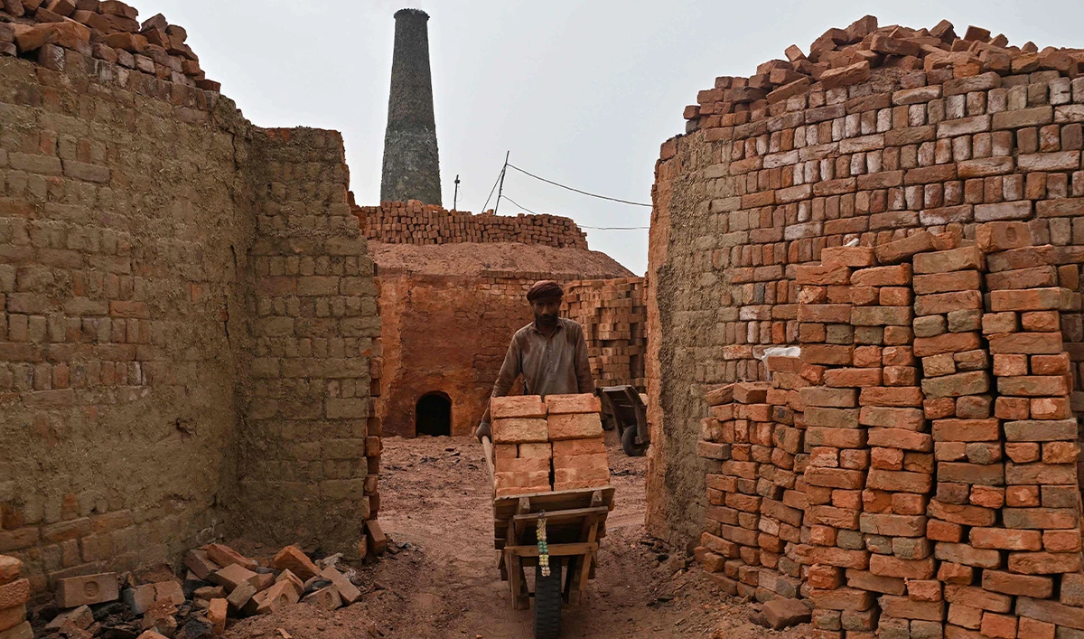 A worker pushes a wheelbarrow at a brick kiln in Sheikhupura district of Pakistan’s Punjab province on July 20, 2026. (AFP)