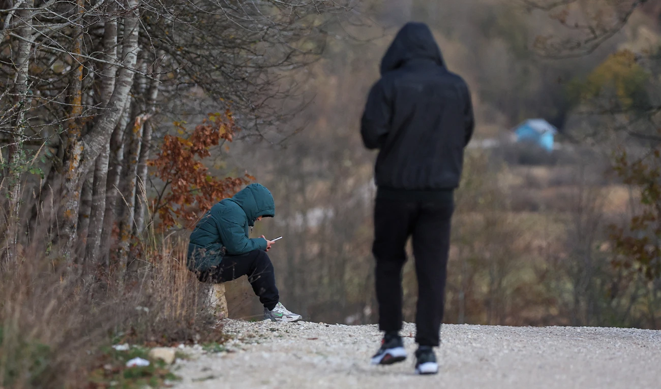 Migrants stand outside Lipa migrant camp, close to Bihac, where many migrants arrive after being pushed back across the Korana river by Croatian police, on November 8, 2023. (AFP/File)