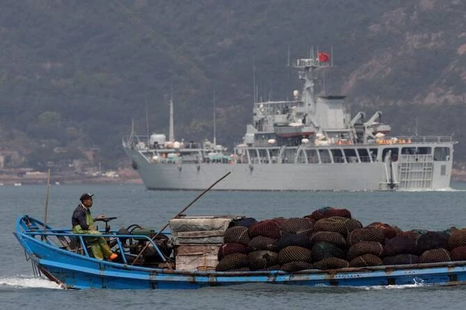 Above, a fishing boat sails past a Chinese warship during a military drill off the Chinese coast near Fuzhou, Fujian Province on April 11, 2023. (Reuters file photo)