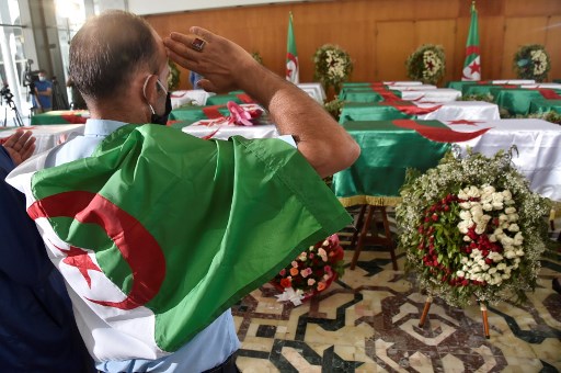 Au Palais de la Culture d’Alger, un homme exécute un salut militaire devant les cercueils contenant les restes de 24 résistants décapités lors de la conquête coloniale de l’Algérie par la France. (Ryad KRAMDI/AFP)