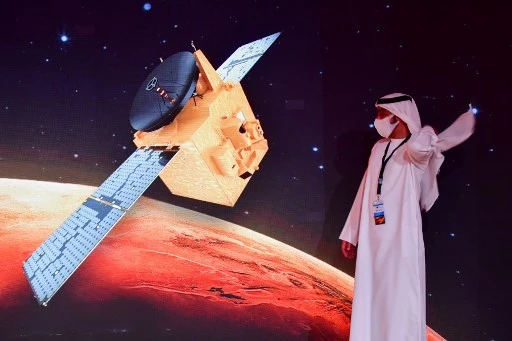 Au Centre spatial Mohammed Ben Rachid, à Dubaï, un homme passe devant un écran sur lequel est projetée la sonde Al-Amal (Giuseppe CACACE/ AFP)