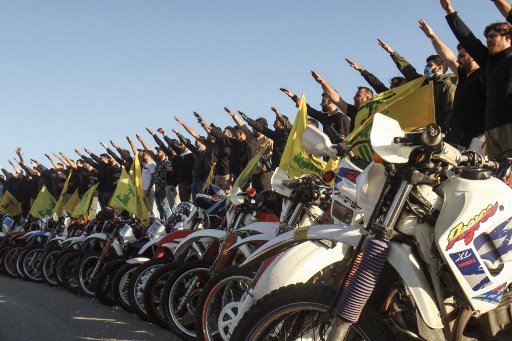 Supporters de la milice chiite du Hezbollah formés en bataillon cycloporté effectuant le salut d’allégeance (Mahmoud Zayat/AFP)