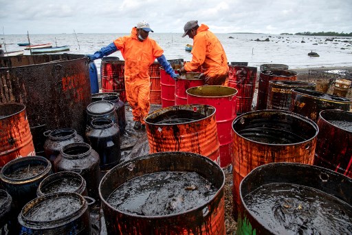 Des ouvriers écopent du fuel déversé sur la plage, à la Rivière des Créoles, le 15 aout, suite au naufrage du tanker MV Wakashio (Fabien Dubessay/AFP)