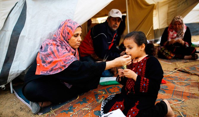 Dans une tente, à proximité du lieu d’affrontement entre les protestataires palestiniens et les forces israéliennes, suite à une manifestation à la frontière avec Israël, une palestinienne donne à manger à sa fille (AFP)