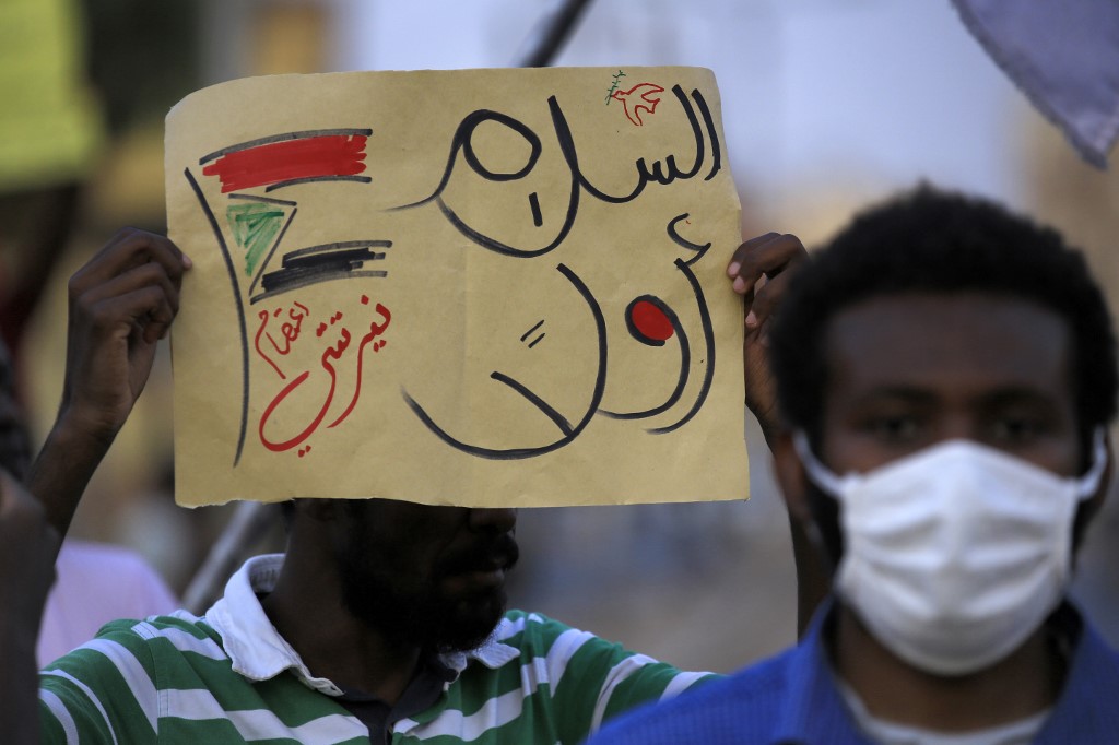Un manifestant brandissant une pancarte en arabe "La paix d'abord", dans le quartier Garden City de la capitale soudanaise Khartoum (Ashraf Shazly/AFP)