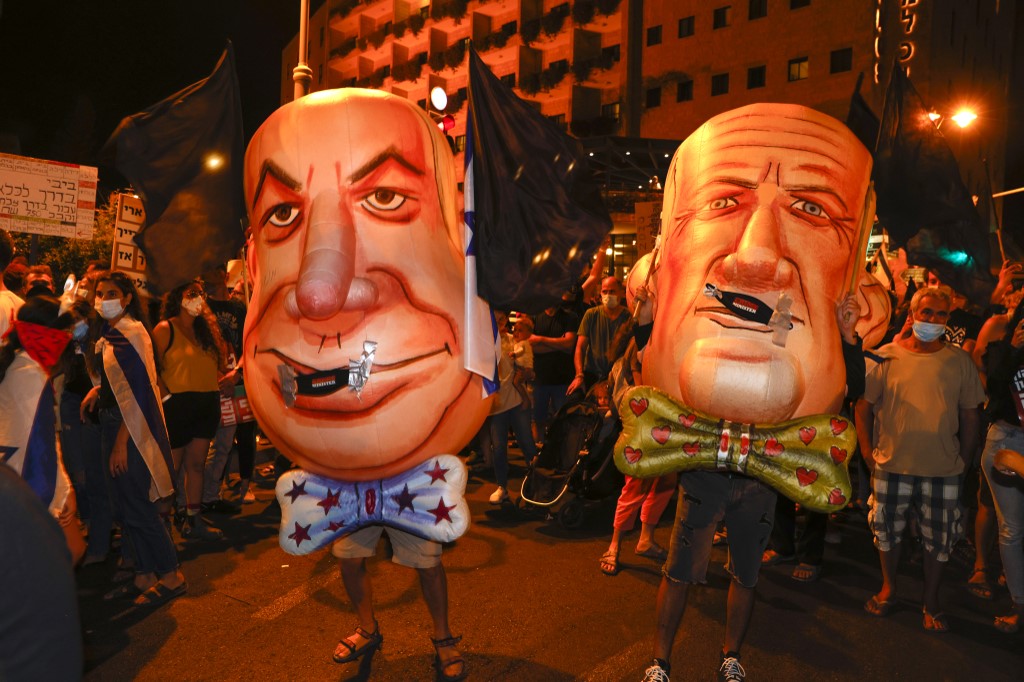 Des manifestants Israéliens arborant des masques géants à l’effigie du Premier ministre Benjamin Netanyahu et de Benny Gantz, vice-Premier ministre du pays (Photo, Manahem KAHANA/AFP).