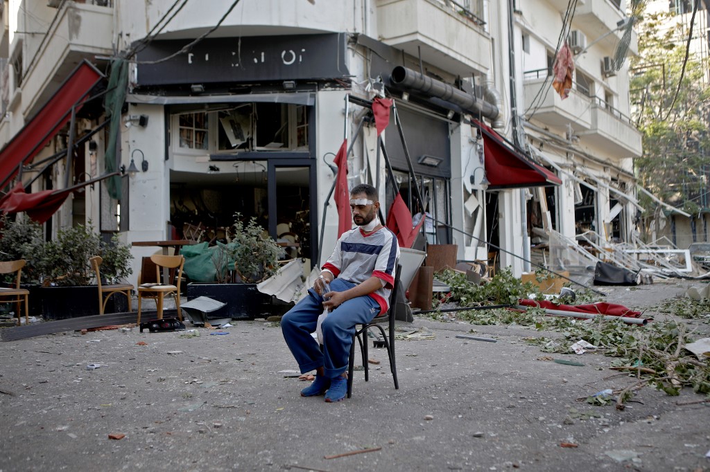 Un homme blessé assis à côté d'un restaurant dans le quartier branché de Mar Mikhael à Beyrouth (Patrick Baz/ AFP)