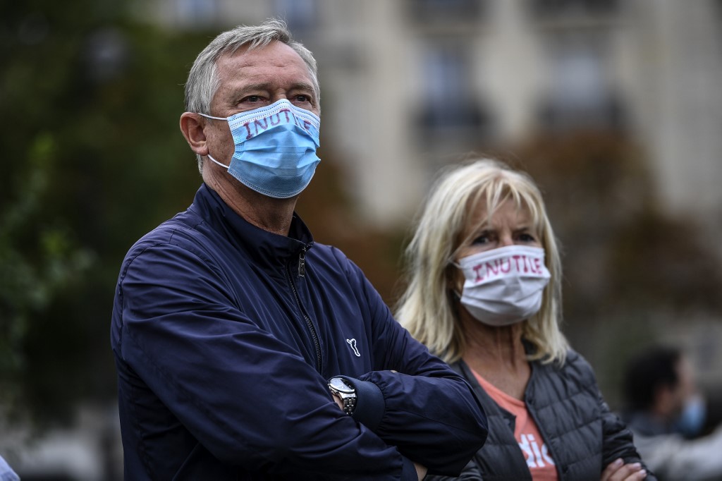 Protestataires portant des masques faciaux marqués "Inutile" lors d'une manifestation contre le port obligatoire des masques à Paris ( Christophe Archambault/AFP)