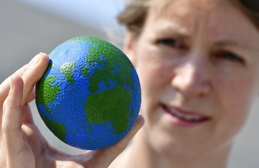 Une orange peinte aux couleurs de la terre. Le jour de dépassement, ou « overshoot day », marque la date à laquelle l’humanité entière a consommé plus de ressource que la Terre ne peut en renouveler (Tobias Schwarz/AFP)
