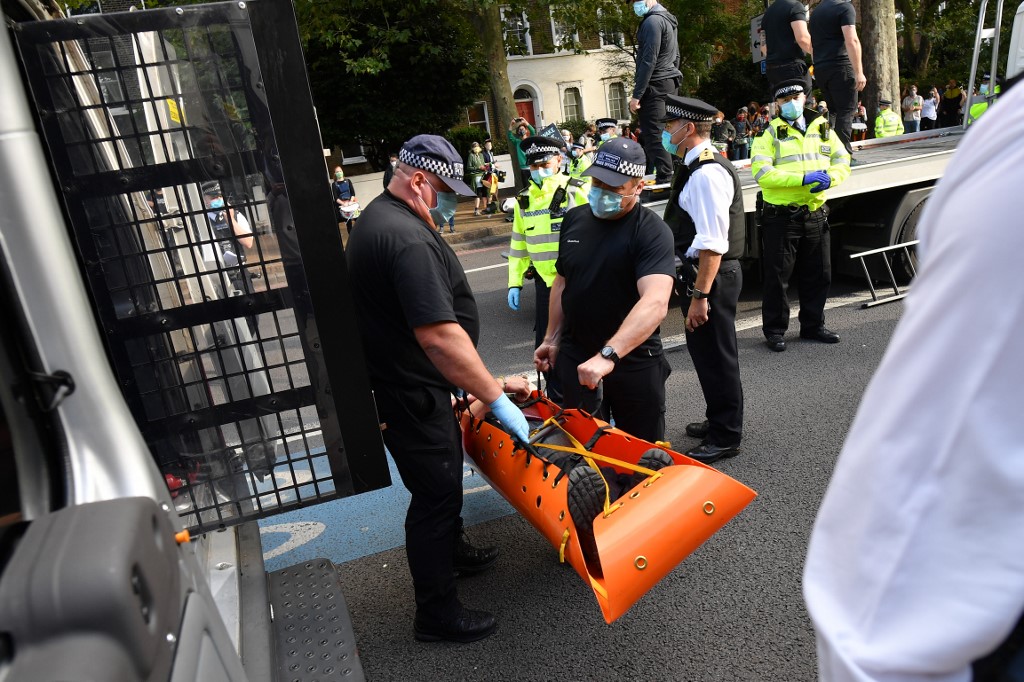 Les agents de police retiennent un activiste d'Extinction Rebellion, qui s'était lui-même collé à un camion près de la station de métro Kennington dans le centre de Londres (Justin Tallis/AFP)