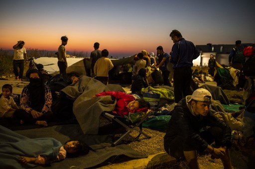 Migrants sur le bord de la route, en Grèce, à proximité de Mytilene, après la destruction de leur camp de Lesbos à l’aube du 11 septembre. (Angelos Tzortzinis/AFP)