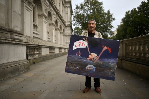 Le caricaturiste Kaya Mar à l’entrée de Downing Street avec un portrait satirique de Boris Johnson en noyé (Ben Stansall/AFP)