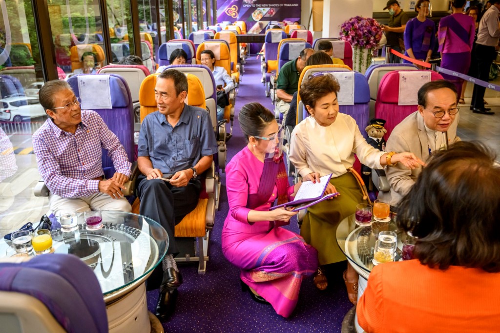 Une hôtesse de l'air de Thai Airways portant un masque facial alors qu'elle sert des clients dans un restaurant sur le thème des avions, au siège de la compagnie aérienne à Bangkok (Mladen Antonov/AFP)