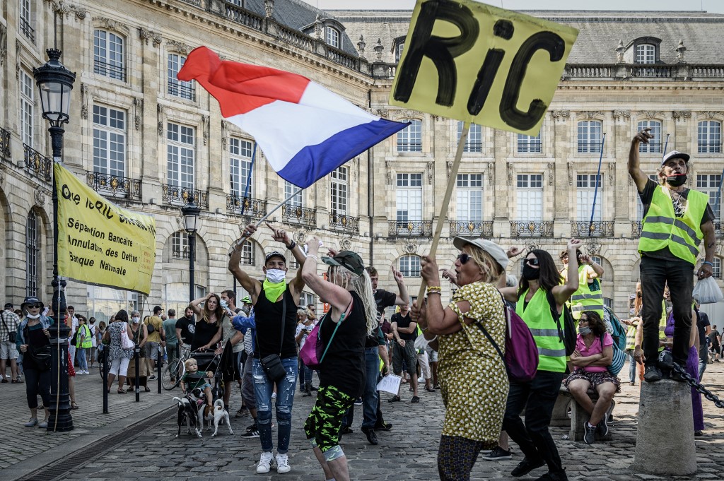 Un manifestant tenant une pancarte indiquant «RIC» pour «référendum d'initiative citoyenne» et une autre agitant un drapeau français, lors d'une manifestation organisée par le mouvement des «gilets jaunes» à Bordeaux. (Philippe Lopez /AFP)