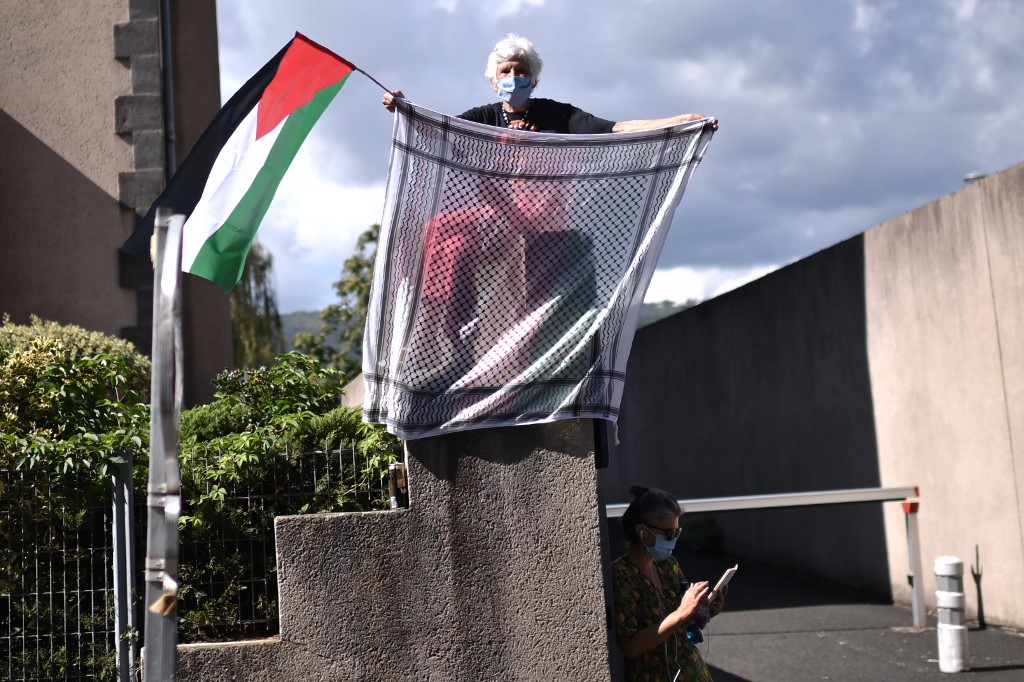 Une femme brandissant keffiyeh et drapeau palestinien lors du Tour de France, le 11 septembre (Photo, Bruno BERTORELLO/AFP).