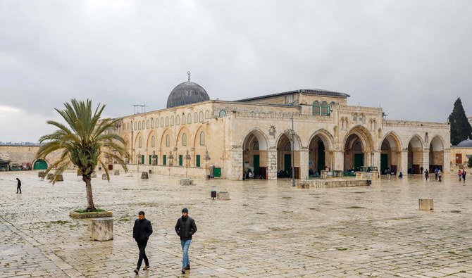 Sur cette photo prise le 20 mars 2020, des Palestiniens marchent devant la mosquée Al-Aqsa, à l'intérieur de l’enceinte presque déserte de la vieille ville de Jérusalem, après que des religieux ont pris des mesures de protection dans le but d'endiguer la propagation du nouveau coronavirus, le 20 mars 2020 (AFP)