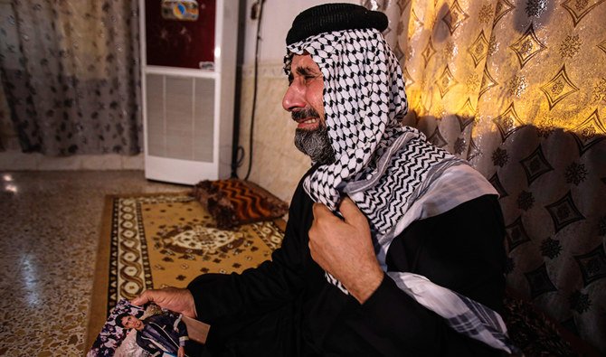 Jasb Hattab Aboud, père du manifestant kidnappé Ali Jasb, pleure en tenant la photo de son fils, dans sa maison de la ville d'Amara, en Irak. (AP)