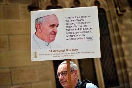 Manifestations pour le climat à Sydney en décembre 2019 : un homme brandit le portrait du pape François (Saeed Khan/AFP)