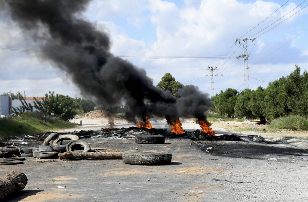 Des jeunes tunisiens brûlent des pneus et bloquent la route menant à la ville de Chebba pour protester contre la décision de la Fédération tunisienne de football. (AFP)