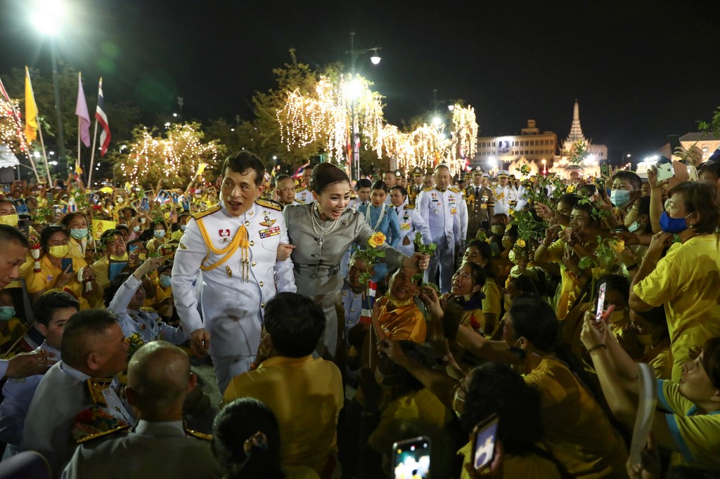 Le roi Maha Vajiralongkorn et la reine Suthida de Thailande accueillent les partisans à l'extérieur du Grand Palais de Bangkok. (AFP)