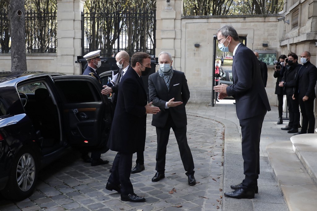Le président français Emmanuel Macron (à gauche) est accueilli par le chef de mission adjoint Wolfgang Wagner (à droite) alors qu'il arrive pour signer un livre de condoléances pour les victimes de l'attentat de Vienne. (Christophe PETIT TESSON / AFP)