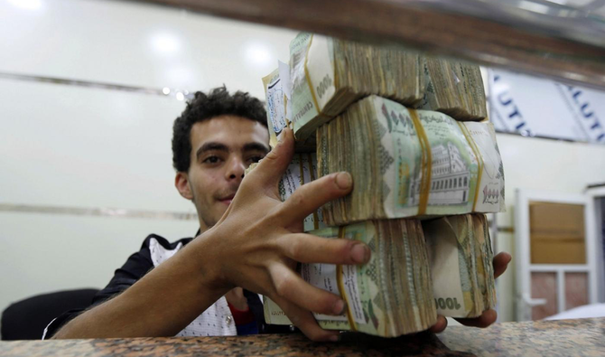 Un agent de change détient des liasses de monnaie yéménite dans un bureau de change à Sanaa, au Yémen. (Reuters/Fichier)