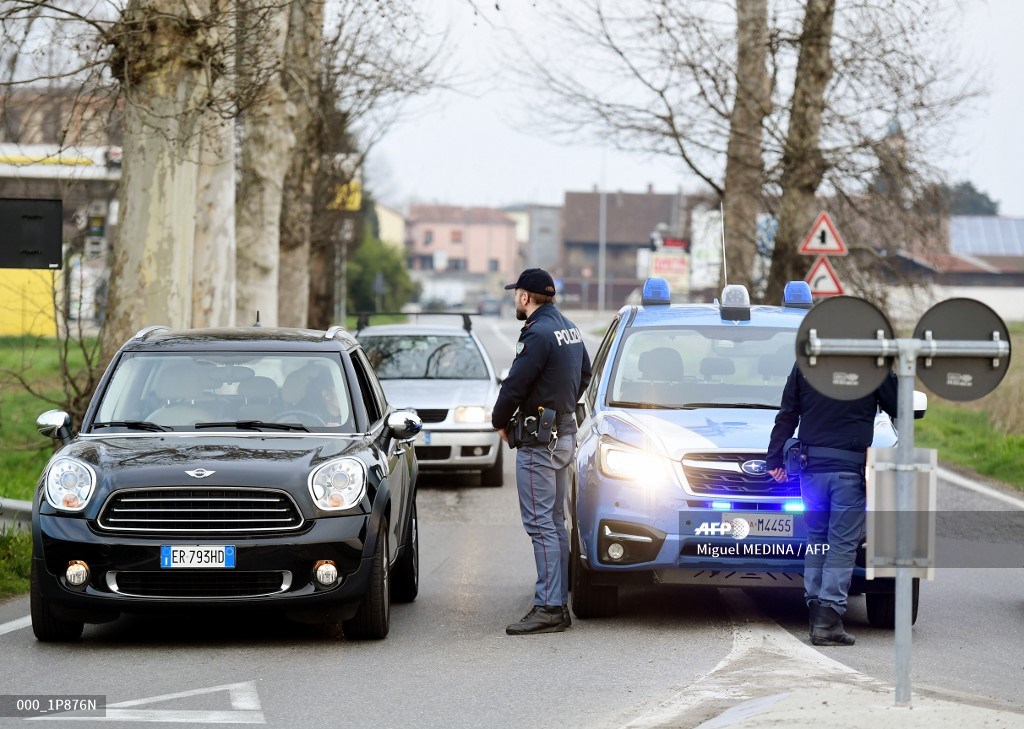 Un officier de la police nationale italienne parle à une personne dans une voiture à l'entrée de la petite ville de Casalpusterlengo, au sud-est de Milan, le 23 février 2020. (AFP).