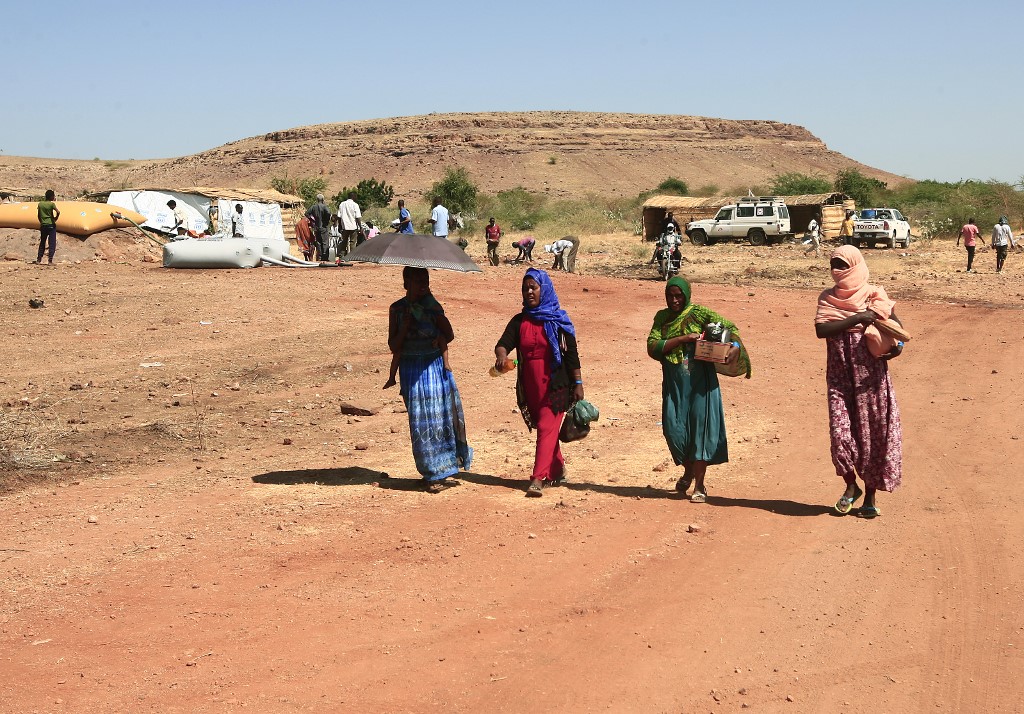 Des réfugiés éthiopiens qui ont fui les combats dans la province du Tigré marchent avec des fournitures dans le camp d'Um Rakuba, dans l'est de la province soudanaise de Gedaref. (AFP)