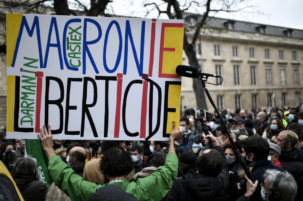 Le militant français Jean-Baptiste Redde alias Voltuan (à gauche) tient une pancarte sur laquelle on peut lire "Macronie Liberticide" lors d'une manifestation organisée par les syndicats de journalistes. (STEPHANE DE SAKUTIN / AFP)