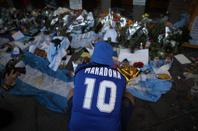 Un fan pleure devant des fleurs et des affiches laissées en hommage à Diego Maradona à l'entrée du stade Boca Juniors