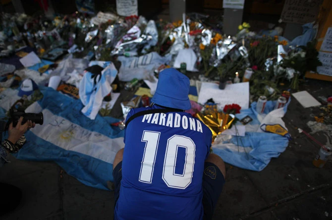 Un fan pleure devant des fleurs et des affiches laissées en hommage à Diego Maradona à l'entrée du stade Boca Juniors